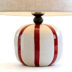Close view of the glossy red and white striped ceramic base and dark wooden neck on this Clérachic table lamp.