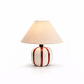 This Clérachic table lamp with red and white stripes, shown lit on a clean white background with a soft shadow.