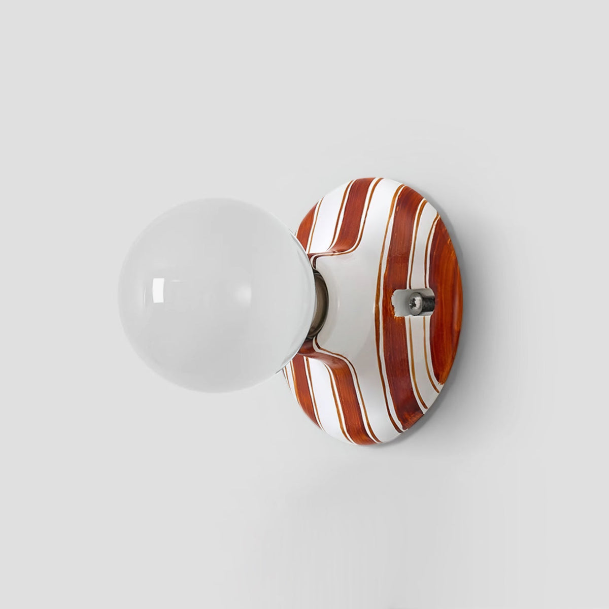 Unlit clear-looking glass globe on a brown and white striped ceramic backplate, this Clérachic wall light on a grey wall.
