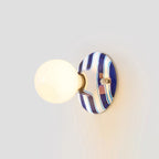 Lit frosted globe on a deep blue and white striped ceramic backplate, this Clérachic wall light on a pale grey wall.