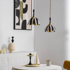 Two small striped pendants with wood finials hang near a round table set with a cup and a cake stand, from Clérachic.