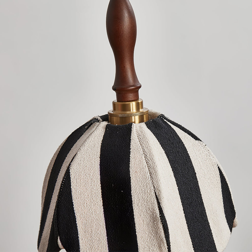 Close view of the knitted black-and-cream stripes, brass collar and turned wood finial on this Clérachic pendant.