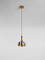 This Clérachic striped pendant hangs from a round brass ceiling canopy on a long brown twisted cord against a grey wall.