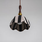 Unlit Clérachic striped pendant seen from below, with the bulb and the darker lining visible inside its scalloped edge.