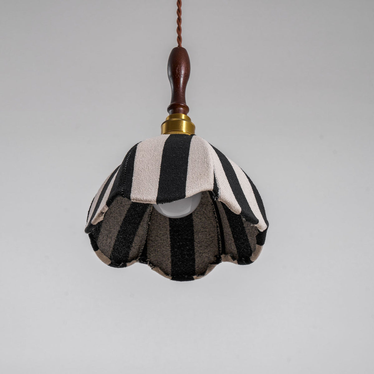 Unlit Clérachic striped pendant seen from below, with the bulb and the darker lining visible inside its scalloped edge.