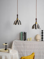Pair of striped fabric pendants above a lace-covered table with books and candles, a yellow chair nearby, from Clérachic.