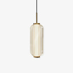 A ribbed glass cylinder pendant with gold fittings, shown lit on a plain off-white backdrop, from Clérachic.