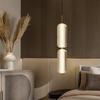 A two-part ribbed glass Clérachic pendant glows beside a bed, with dried pampas grass and a rattan-fronted cabinet behind.