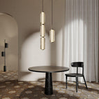 Two Clérachic ribbed glass pendants, one in three tiers, hang over a round dark table and a black chair on a tiled floor.