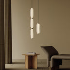 A three-tier and a single ribbed glass Clérachic pendant hang in a warm beige room, beside a low wooden table and a lounge chair.