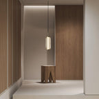 A single ribbed glass Clérachic pendant hangs in a bright passage, with a carved wooden stool and panelled walls beyond.