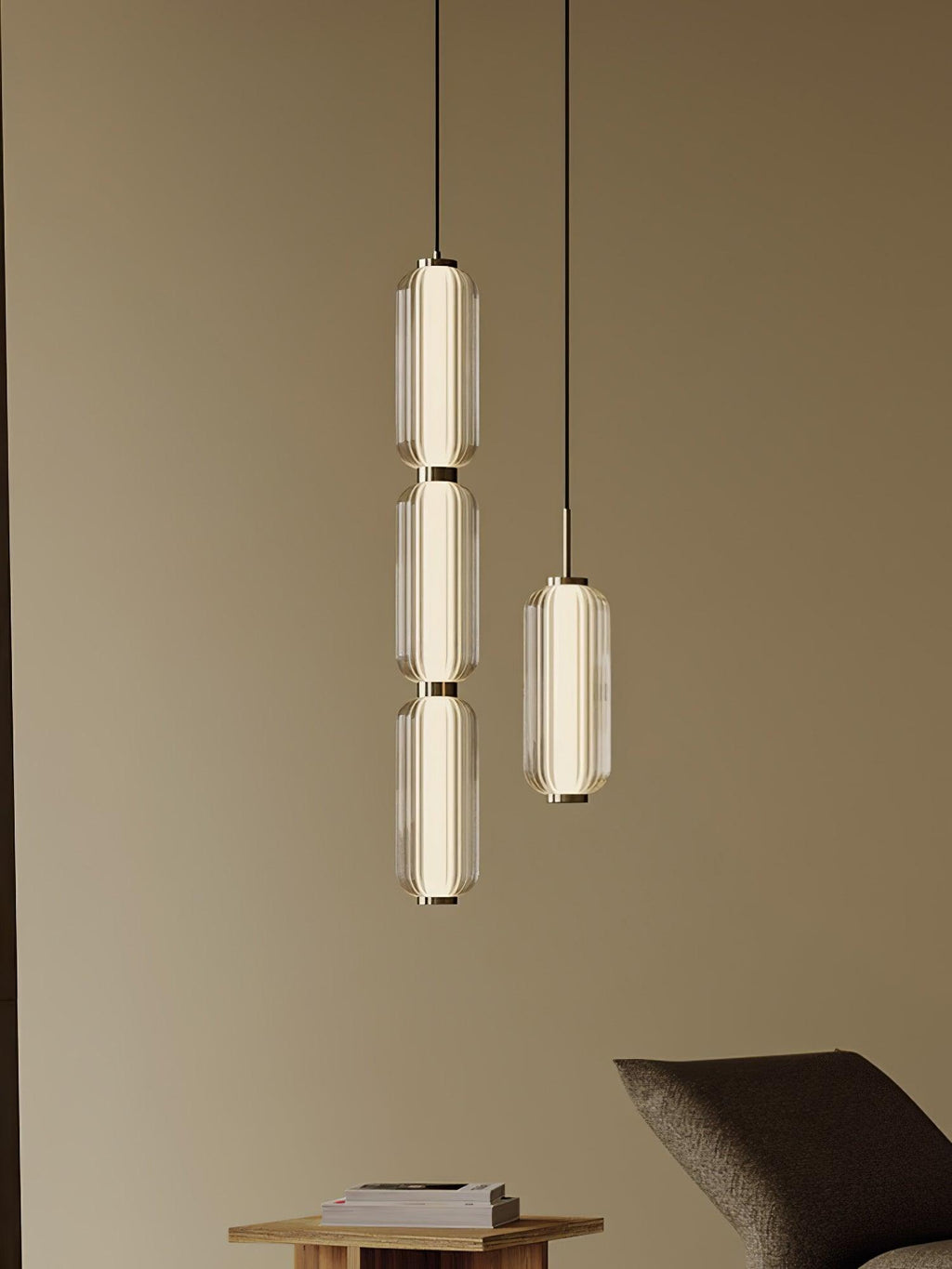 A three-tier and a single ribbed glass Clérachic pendant hang together in a warm room, above a low table and a lounge chair.
