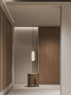 A single ribbed glass Clérachic pendant hangs over a wooden stool in a passage with panelled walls and a strip of ceiling light.