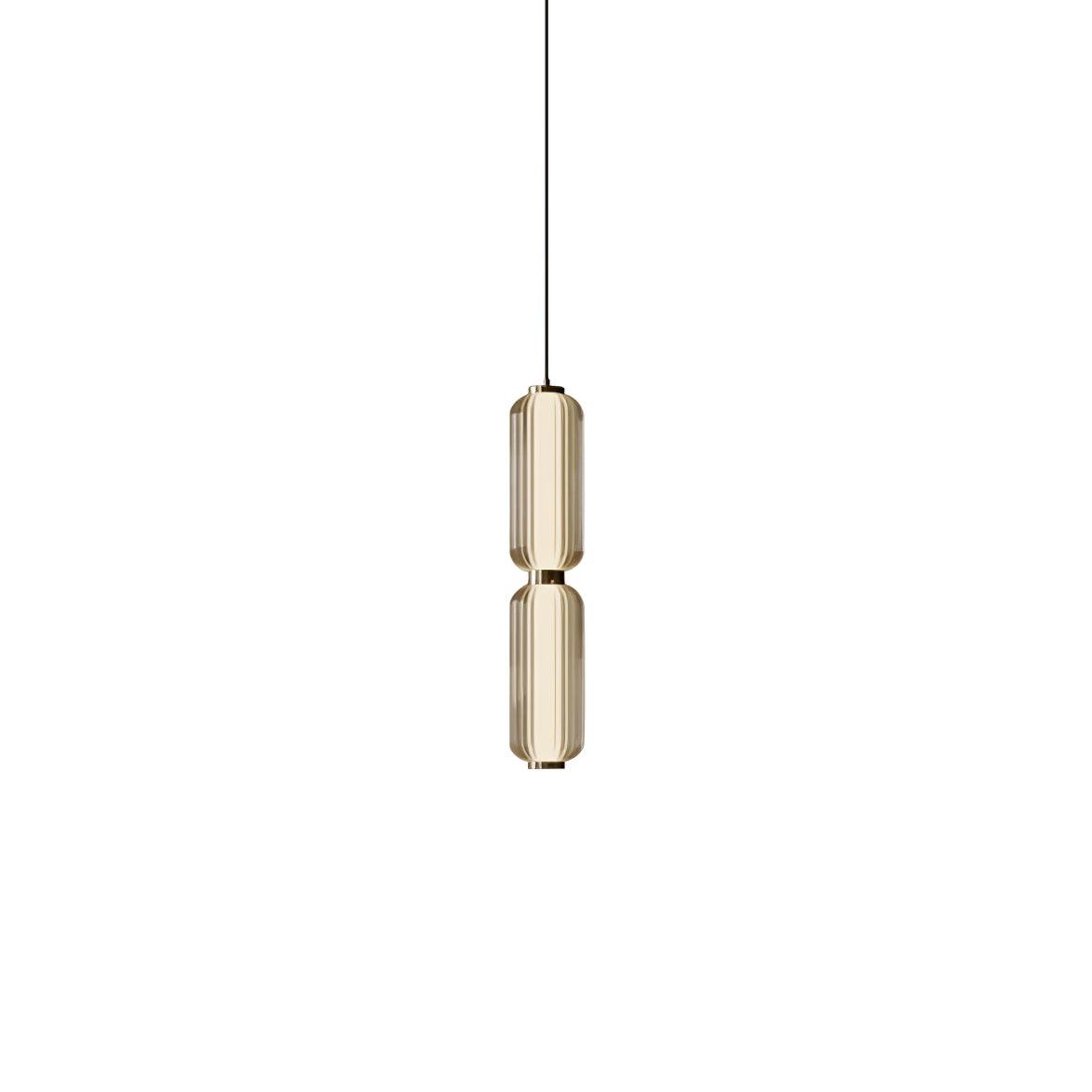 A slim two-tier Clérachic pendant in champagne-tinted ribbed glass with gold collars, on a plain white backdrop.