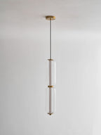A two-tier Clérachic ribbed glass pendant hangs from a gold canopy on a thin black cord, unlit against a pale wall.