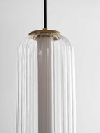 Close view of the top of a ribbed clear glass Clérachic pendant, showing the gold canopy cap and white inner tube.