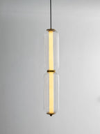 A two-tier ribbed clear glass Clérachic pendant lit with a warm inner tube, hanging on a thin cord against grey.