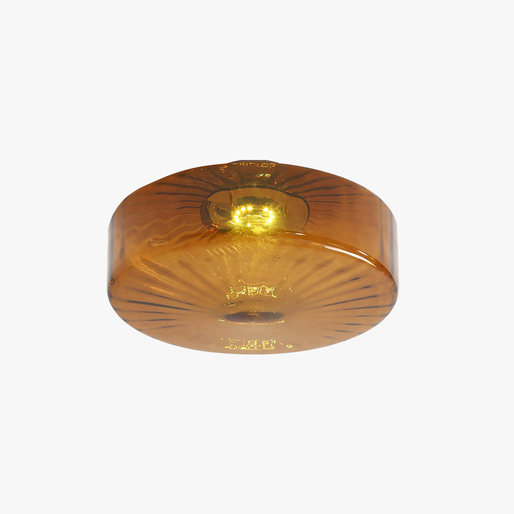 Studio view of the Clérachic Sunburst Amber Glass Flush Mount Ceiling Light, the radial sunburst pressed into the glass catching the light.