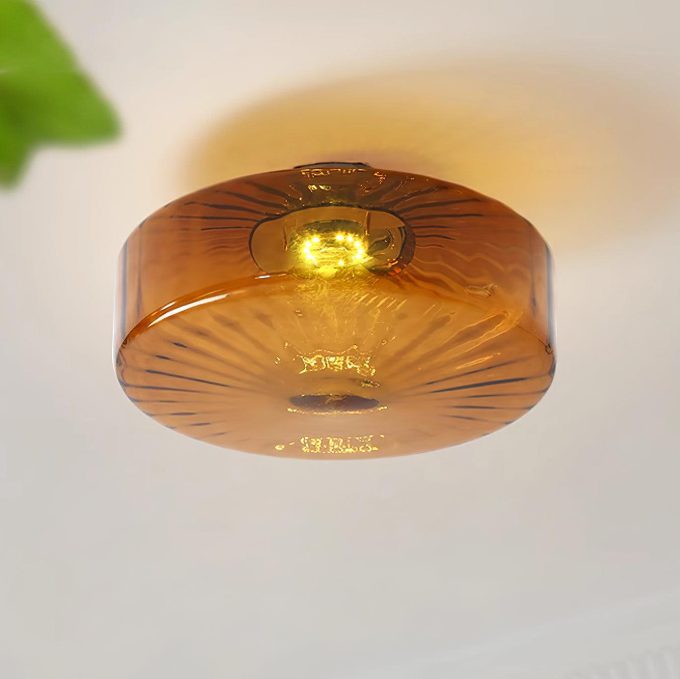 Clérachic Sunburst Amber Glass Flush Mount Ceiling Light glowing above a corner where a green plant leans into the frame.