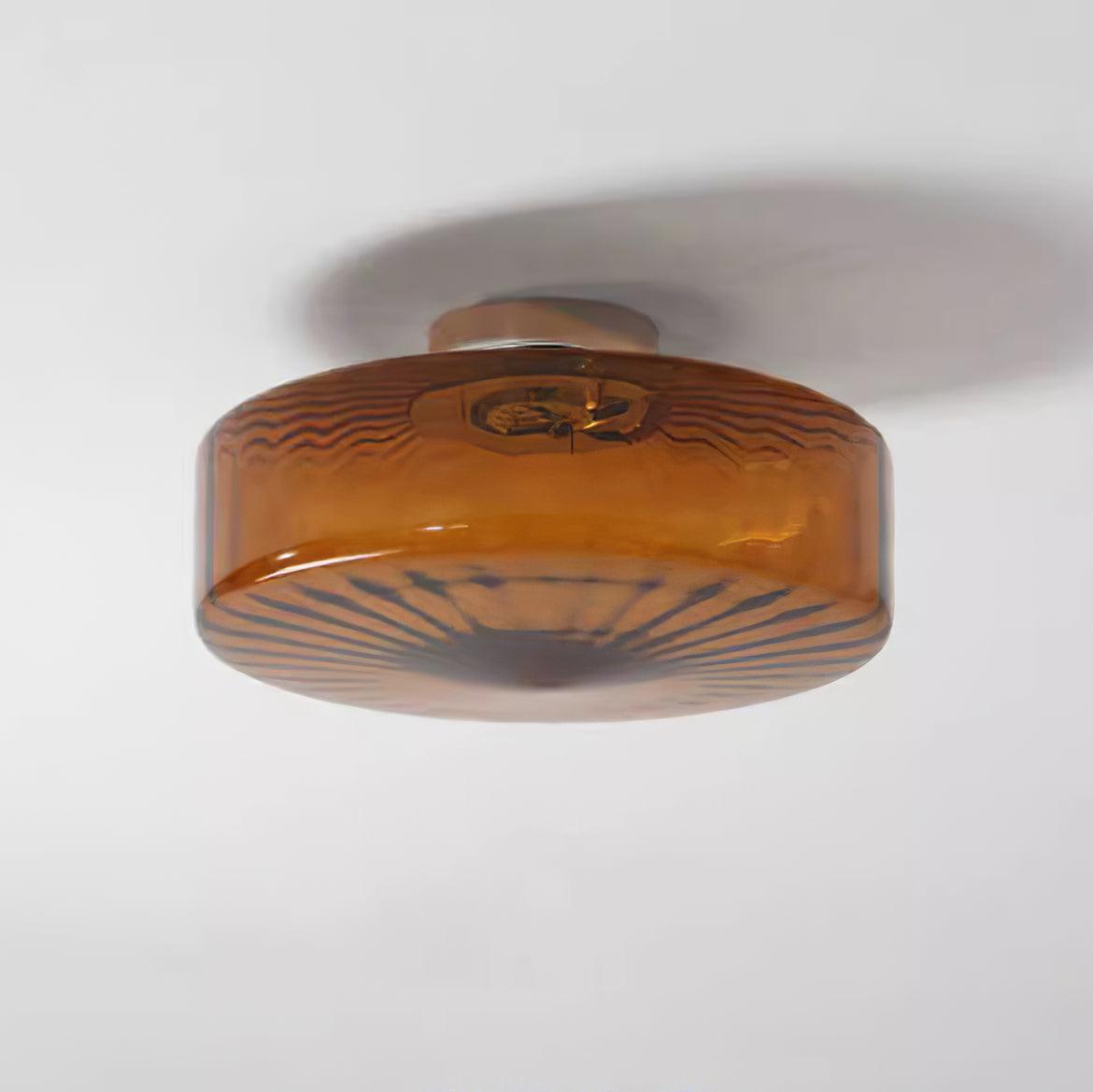 Angled ceiling view of the Clérachic Sunburst Amber Glass Flush Mount Ceiling Light, the short chrome canopy holding it flat to the plaster.