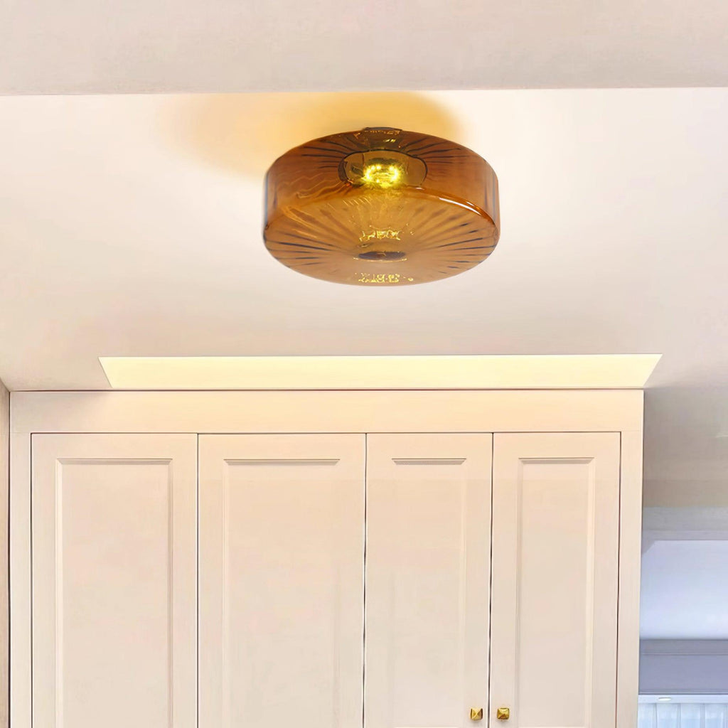 Clérachic Sunburst Amber Glass Flush Mount Ceiling Light mounted above tall white cabinets with brass handles in a bright utility corner.