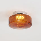 Clérachic Sunburst Amber Glass Flush Mount Ceiling Light lit on a white ceiling, the polished chrome canopy visible above the amber drum.