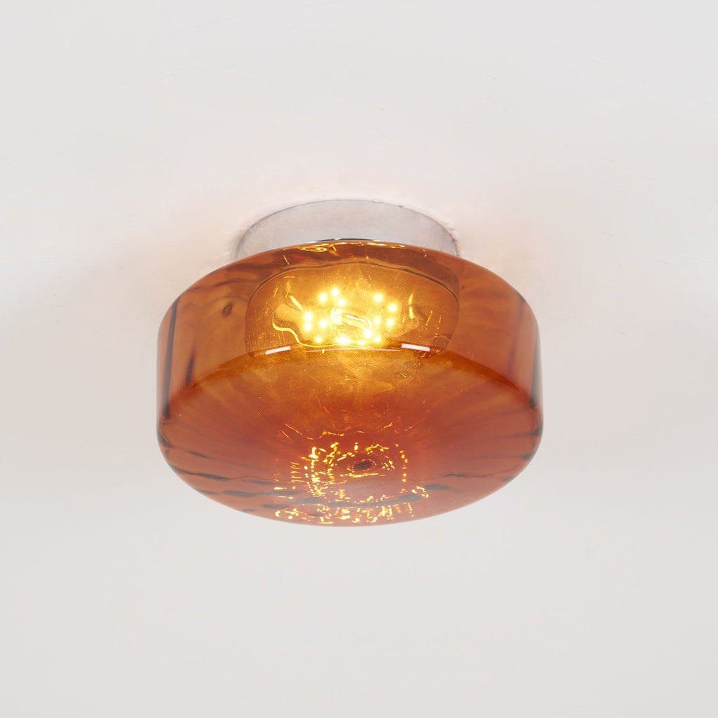 Clérachic Sunburst Amber Glass Flush Mount Ceiling Light lit head-on, the warm LED bloom spreading through the pressed glass shade.