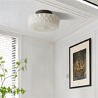 Clérachic fluted white glass flush ceiling light under a panelled white ceiling, beside a framed print and a slatted window.