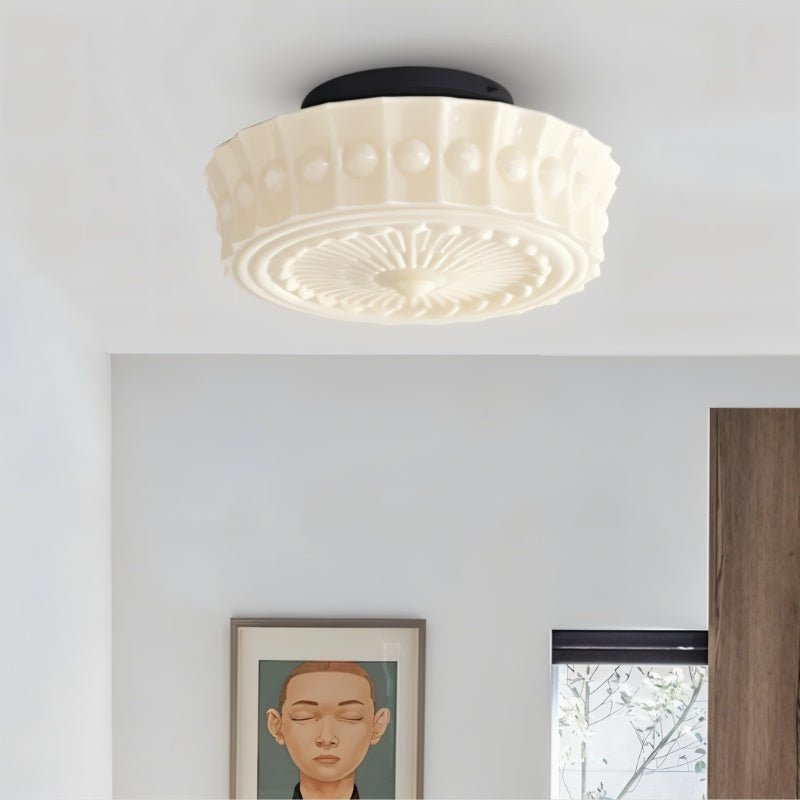 Clérachic cream beaded glass flush ceiling light close up, sunburst base and black plate, above a framed portrait and window.