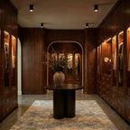 Clérachic surface downlight fixtures light a walnut walk-in closet with a round table, vase and patterned rug.