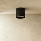 Clérachic compact black cylindrical downlight with two fine grooves, switched off, fixed to a limewashed plaster ceiling.