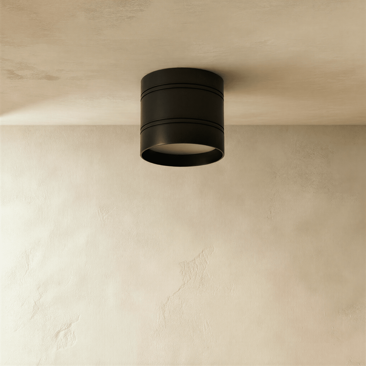 Clérachic compact black cylindrical downlight with two fine grooves, switched off, fixed to a limewashed plaster ceiling.