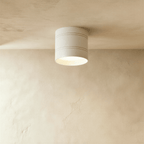 Clérachic compact white cylindrical downlight with two fine grooves, lit softly and fixed to a limewashed plaster ceiling.