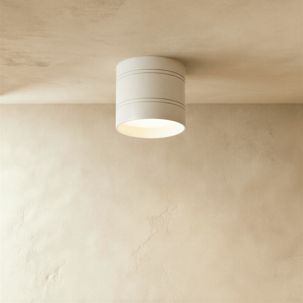 Clérachic compact white cylindrical downlight with two fine grooves, lit softly and fixed to a limewashed plaster ceiling.
