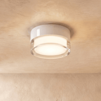 Clérachic white round flush ceiling light with a clear acrylic edge around a softly lit frosted centre, on a limewash ceiling.