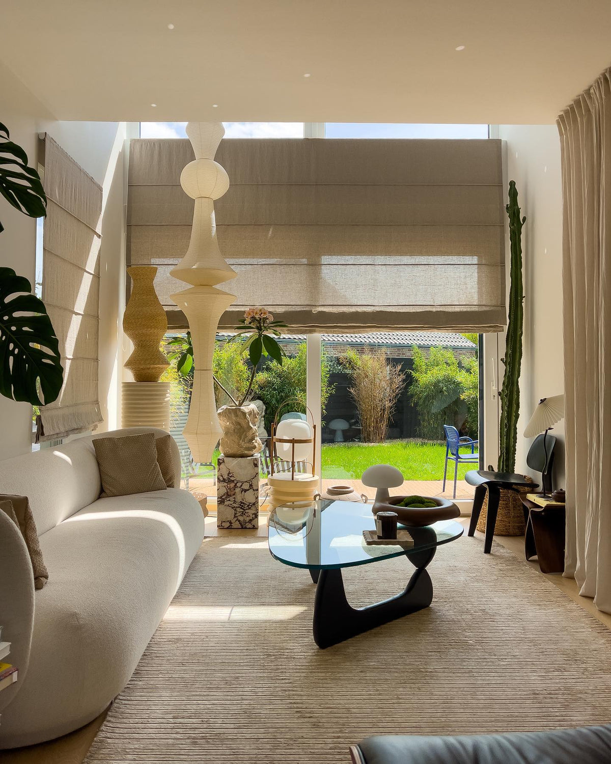 Clérachic washi paper pendant seen in daylight across a sunlit living room, its stack rising past linen blinds and a tall cactus.