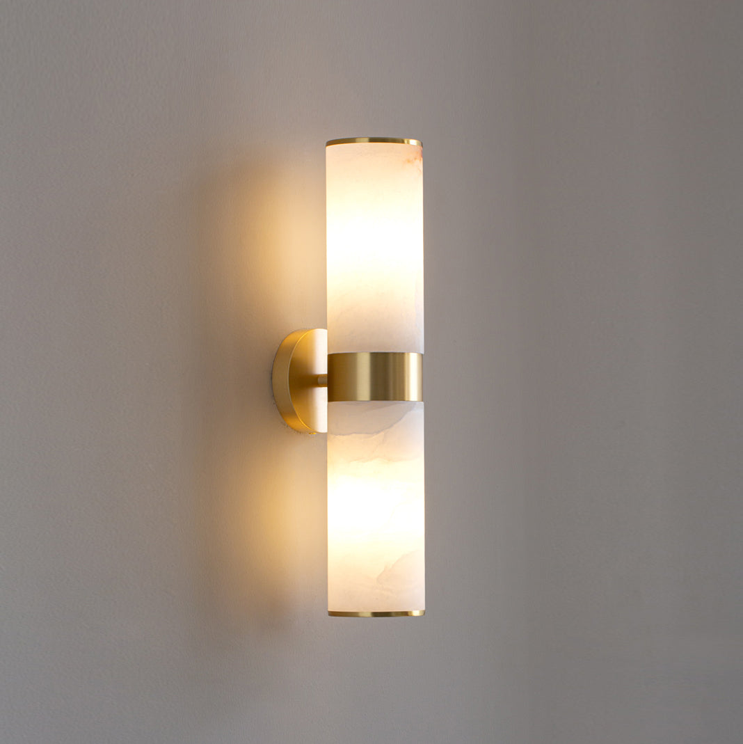 Clérachic brass Sway sconce lit head on, its warm light washing the wall in a soft vertical halo.