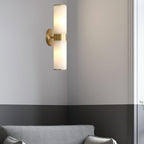 The Clérachic Sway on a corner wall above a grey sofa, its brass stem catching the daylight.