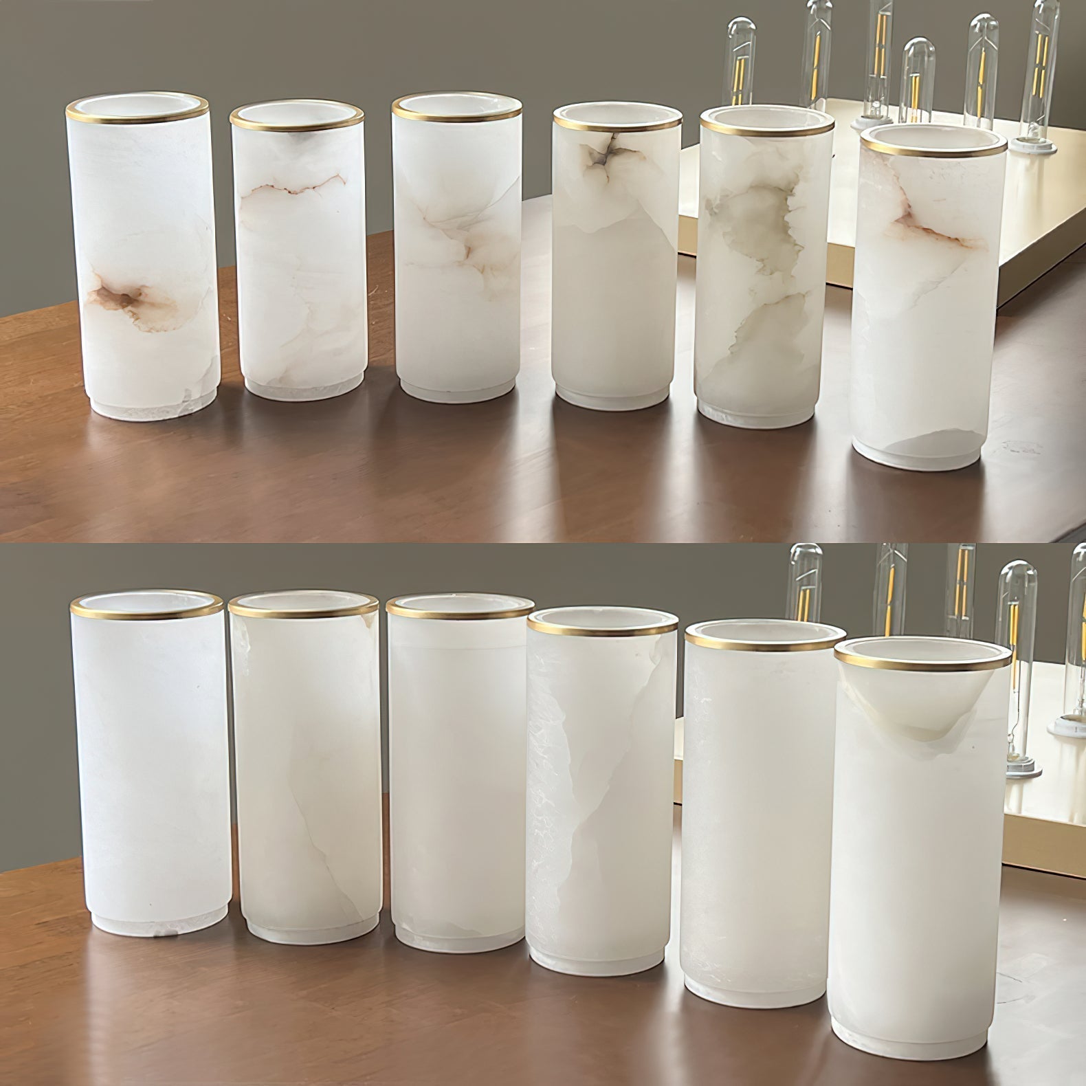 Clérachic alabaster shades lined up on a walnut table with brass rims and tubular filament bulbs behind.