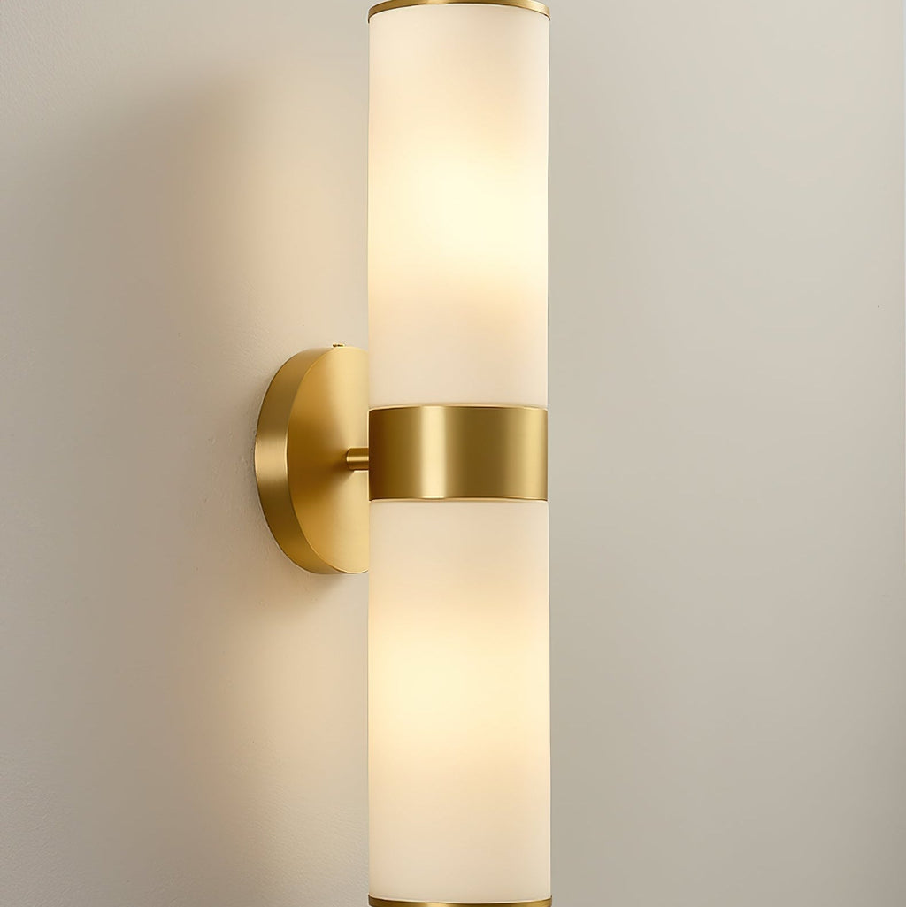 The Clérachic Sway at full length on a cream wall, brass backplate and collar framing the stone tubes.