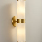 The Clérachic Sway at full length on a cream wall, brass backplate and collar framing the stone tubes.