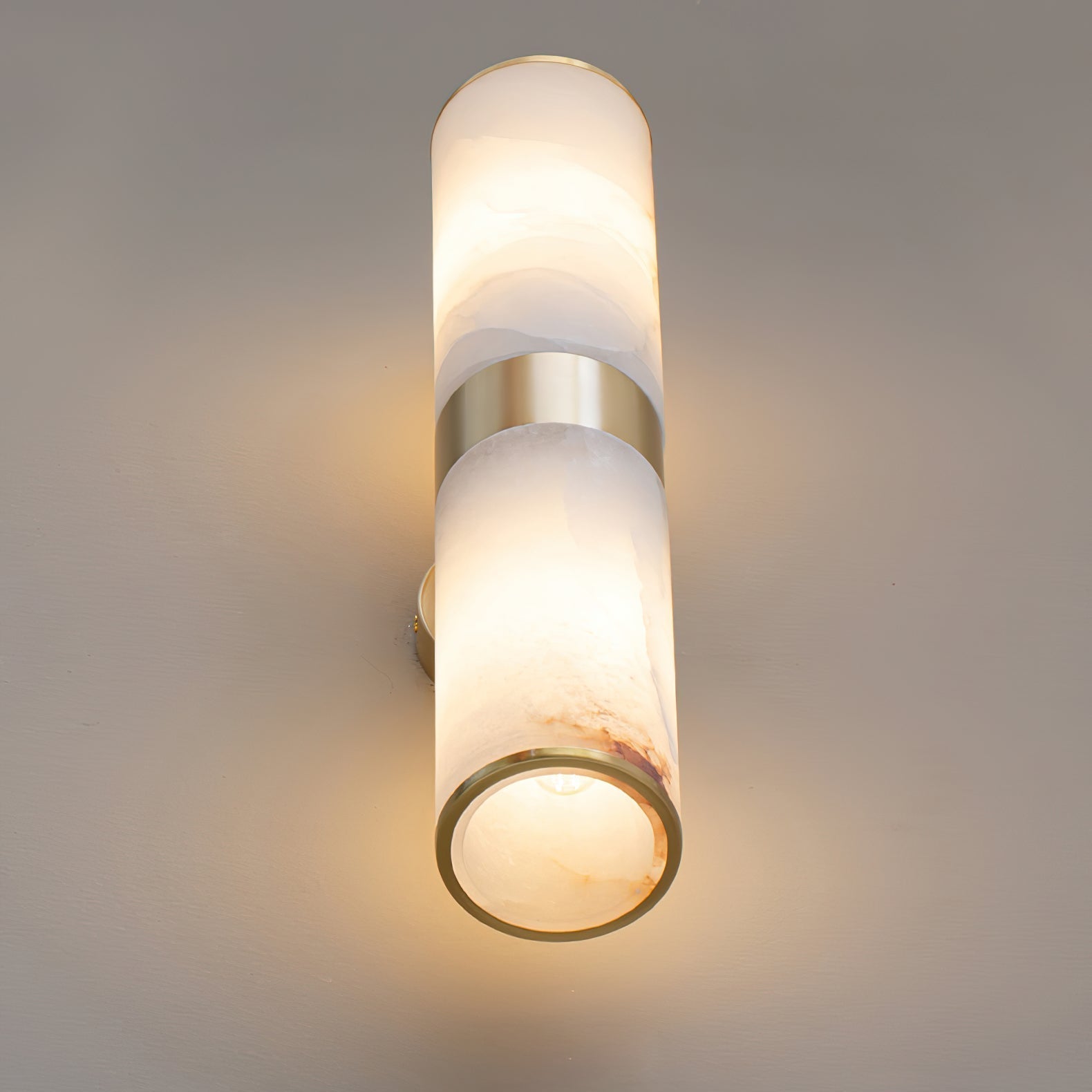Clérachic Sway seen from below, the open brass rim revealing warm light inside the alabaster tube.