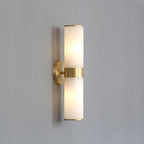 The Clérachic Sway unlit on a pale grey wall, showing the slim brass arm and matched stone cylinders.