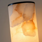 Clérachic alabaster shade in macro, backlit so amber and rust veining glows through the natural stone.