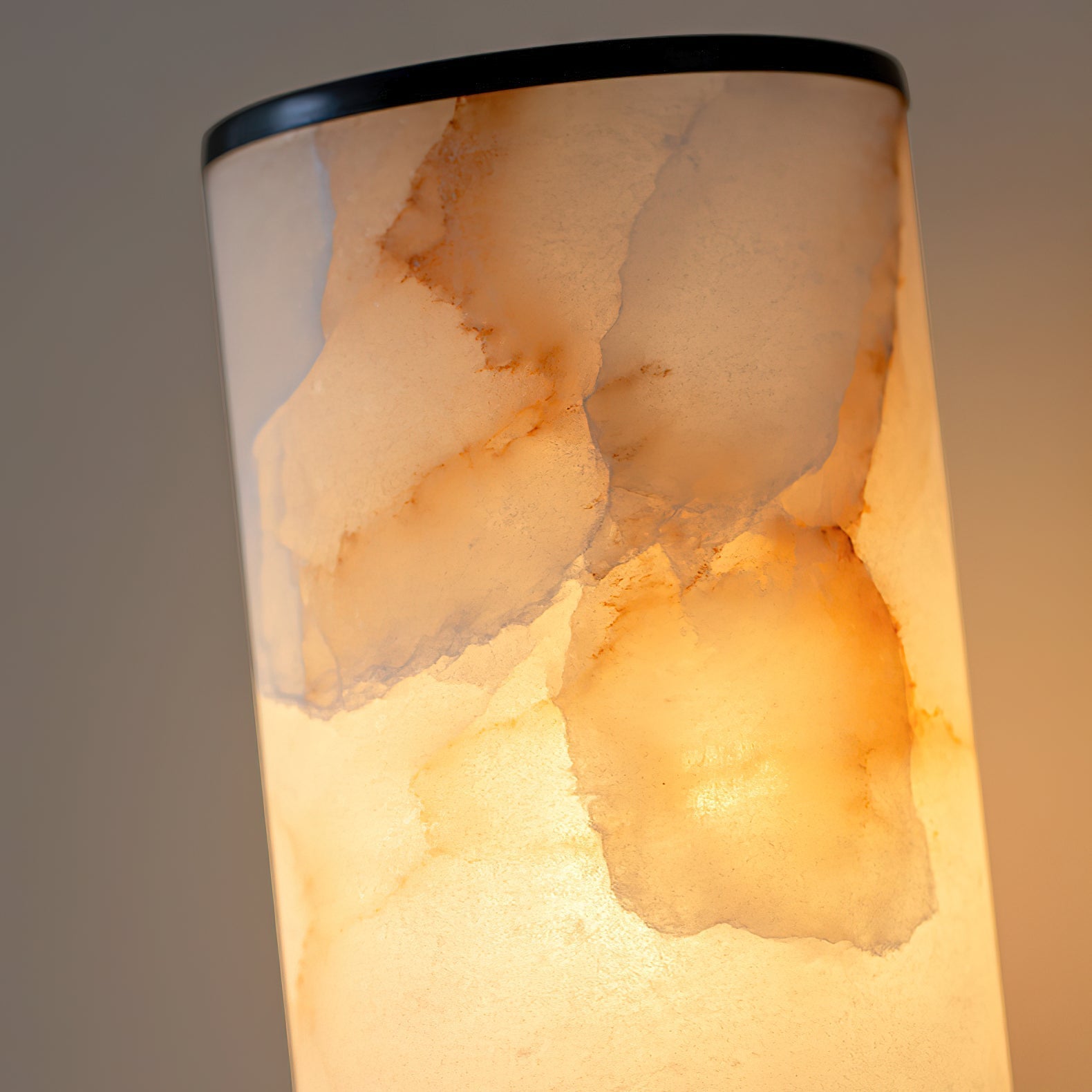 Clérachic alabaster shade in macro, backlit so amber and rust veining glows through the natural stone.