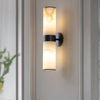 The Clérachic Sway in black finish, lit beside a window, amber veining showing through the alabaster.