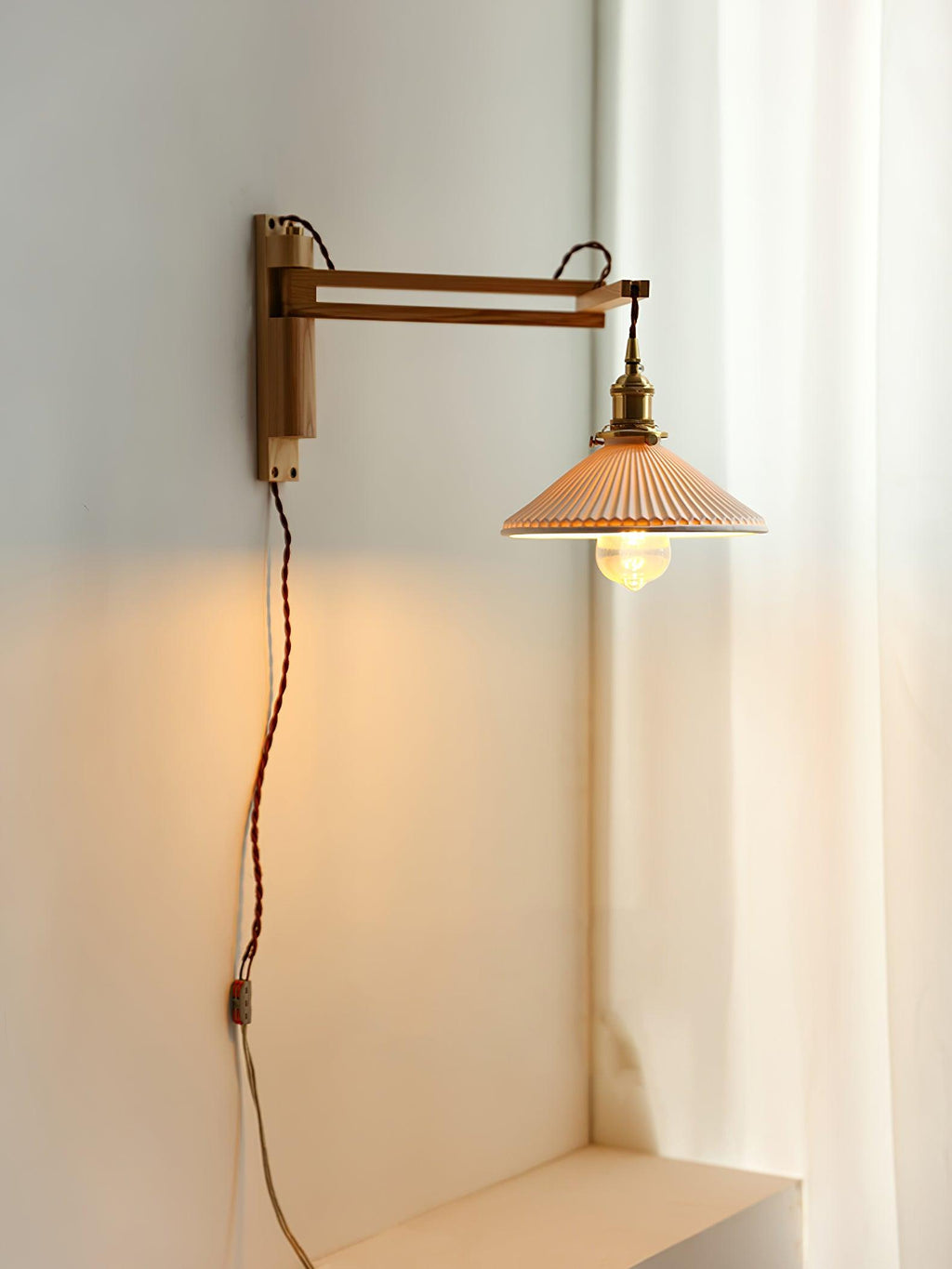 Tall view of a Clérachic swing-arm wall light beside a white curtain, with its flex running down the wall to the plug end.