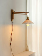 Tall view of a Clérachic swing-arm wall light beside a white curtain, with its flex running down the wall to the plug end.