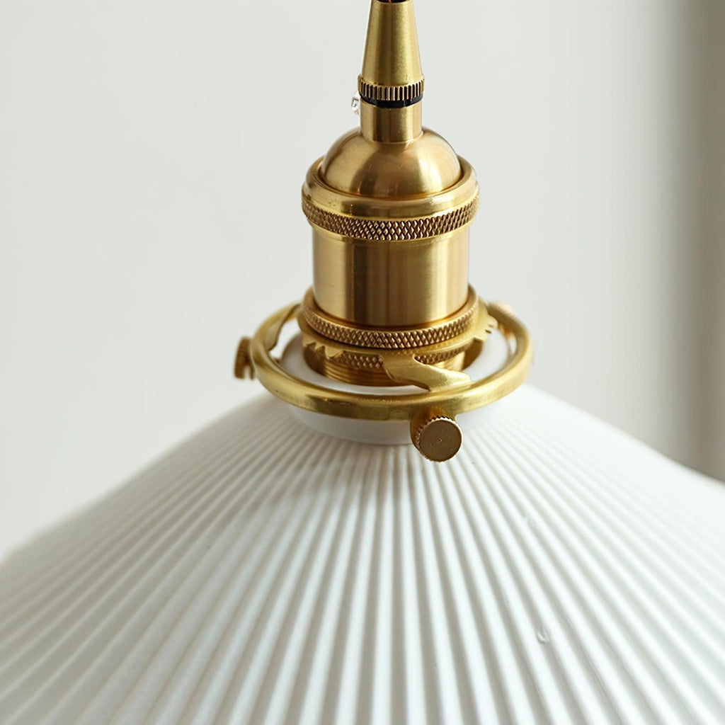 Close view of the knurled brass socket and the fine ribs of the pleated white ceramic shade on this Clérachic wall light.