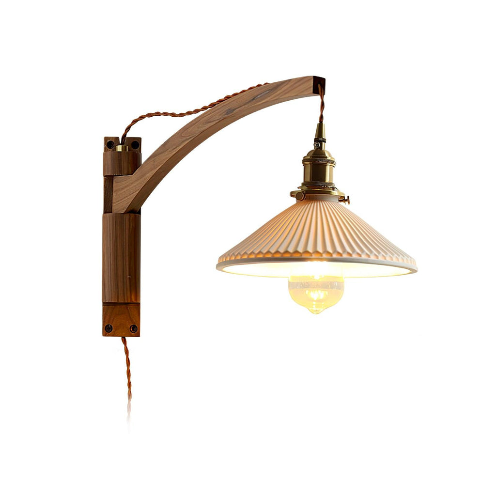 This Clérachic wall light on a plain white backdrop, its curved walnut arm meeting a pleated white shade and a visible bulb.